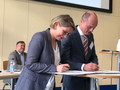 Bildungsministerin Dr. Stefanie Hubig und Dr. Markus Warnke, Wübben Stiftung, stehen an Stehtisch und unterzeichnen Kooperationsvereinbarung