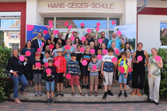 Gruppe aus Schülern, Lehrern, Ministerin vor Schuleingang mit lila Punkten in der Hand